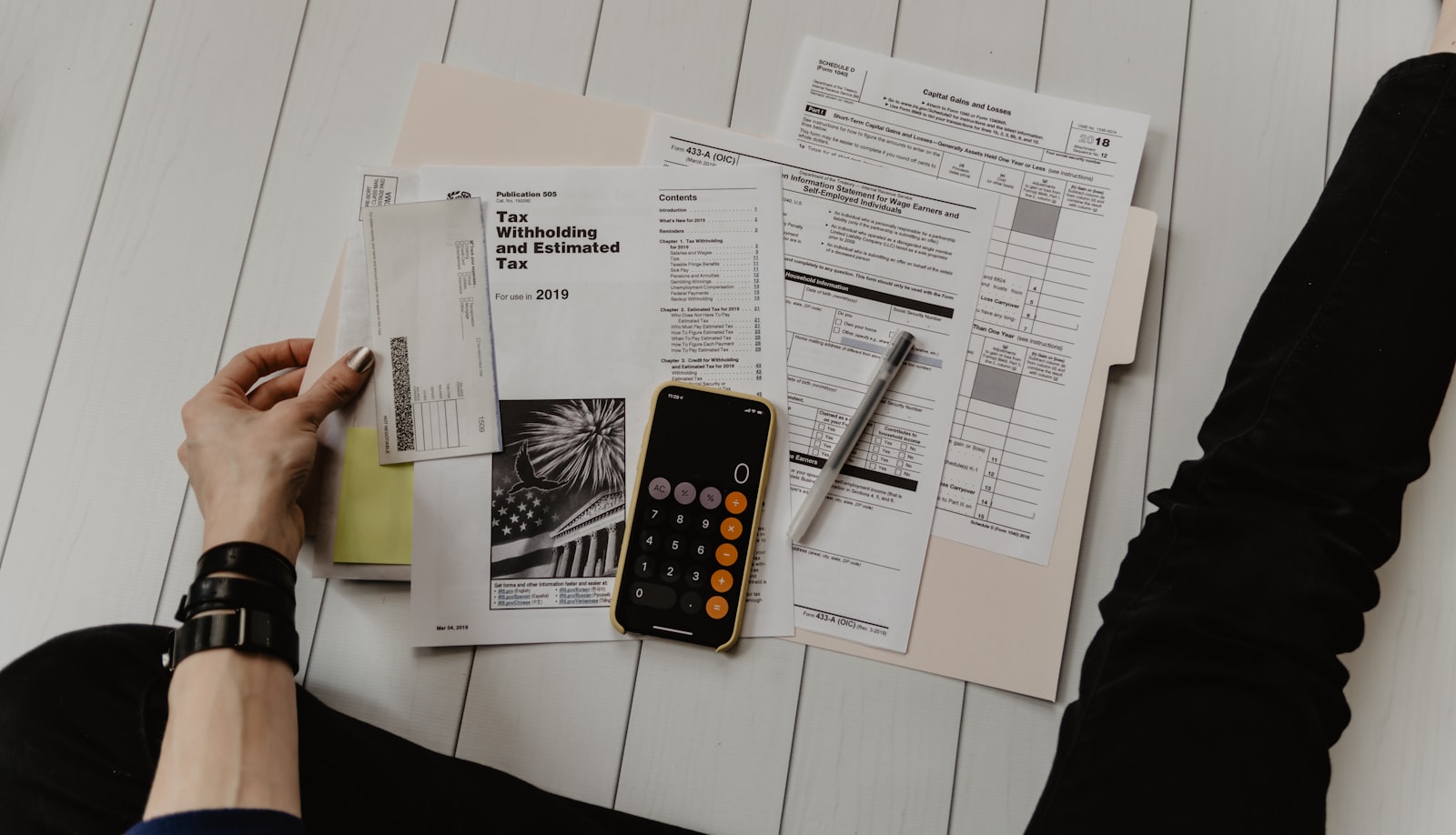 Person comparing 2027 health insurance plan costs with paperwork, pen, and calculator